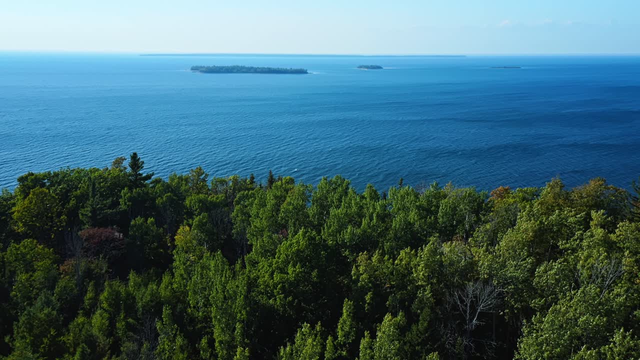 Aus erhöhter Warte trifft das grüne Blätterdach des Waldes von Door County auf das weite Blau des Michigansees, mit verstreuten Inseln, die in der Ferne unter klarem Mittagslicht ruhen.