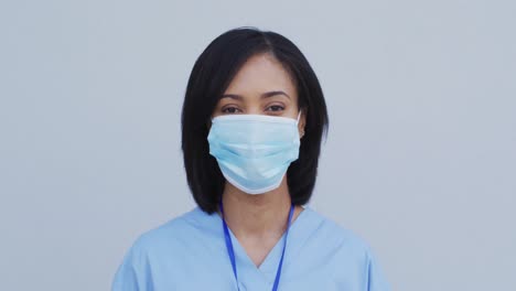 Portrait-of-Female-health-worker-wearing-face-mask-against-white-background