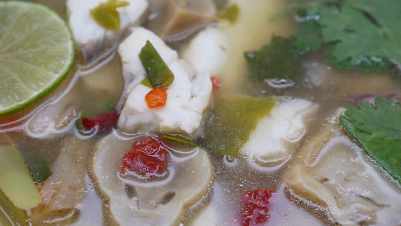imágenes de primer plano de la sopa tom yum clara con lubina y champiñones, la famosa comida tailandesa conocida por su sabor aromático y picante