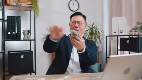 happy rich successful businessman throwing sharing money dollar cash big profit winning at office