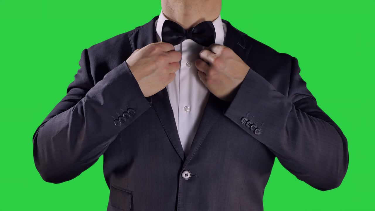 manos arreglando corbata negra, fondo de pantalla verde, ceremonia traje negro
