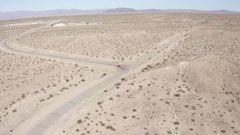 Vista-Aérea-Siguiendo-Un-Coche-Rojo-Conduciendo-Por-El-Desierto