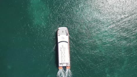 Video-De-Seguimiento-De-Drones-Aéreos-Del-Ferry-Utila-Dream-En-El-Azul-Profundo-Del-Mar-Caribe-Abierto,-Llegando-A-La-Isla-De-Utila,-Honduras