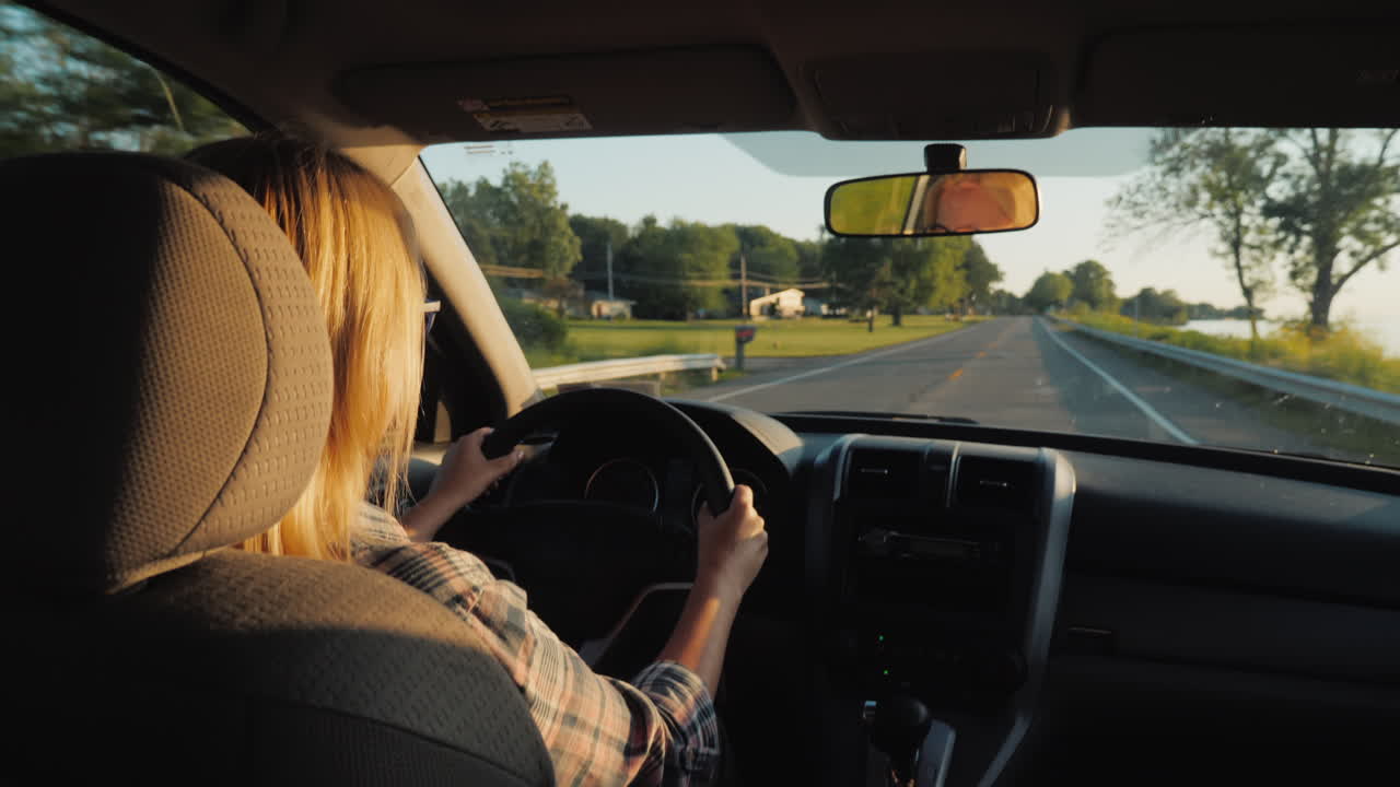 vista trasera de una mujer de mediana edad conduciendo un automóvil en los suburbios de los estados unidos