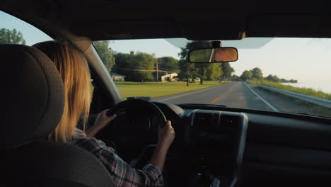 Vista-Posterior-De-Una-Mujer-De-Mediana-Edad-Conduciendo-Un-Automóvil-En-Los-Suburbios-De-EE.-UU.
