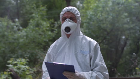 researcher in protective suit in forest