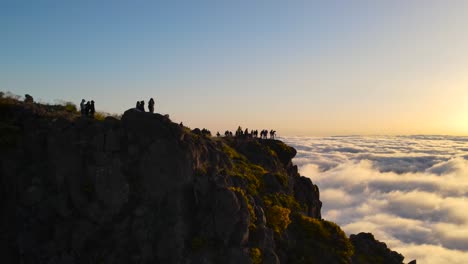 mountain top of pico do arieiro on madeira island portugal and silhouettes of many tourists watching the sunset above the clouds