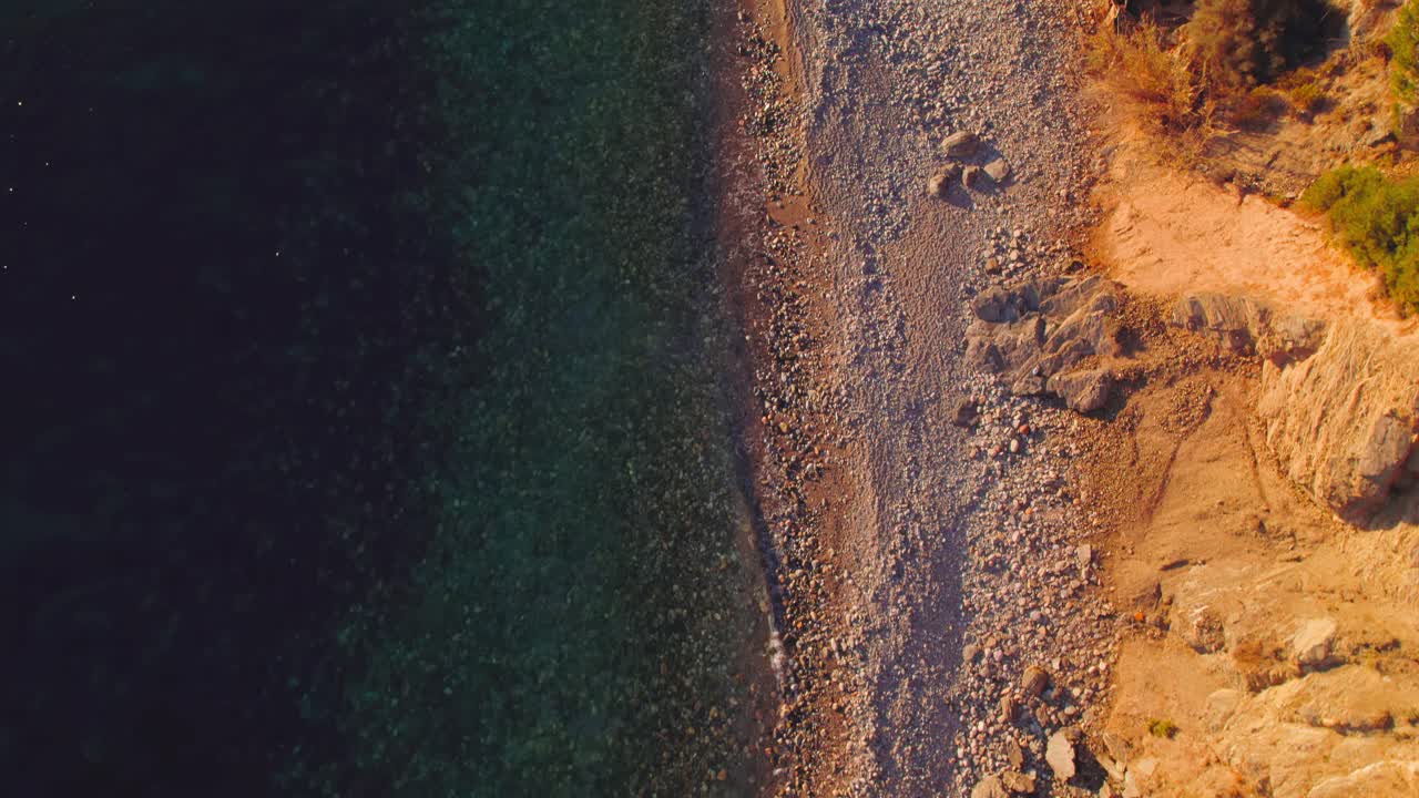 Vista a volo d'uccello della costa della spiaggia al tramonto, inclinando la ripresa verso l'orizzonte per rivelare le colline vicino alla costa