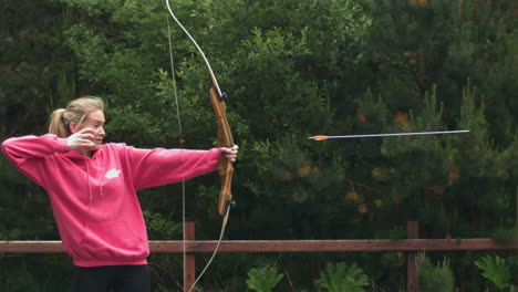 blonde woman shooting bow and arrow