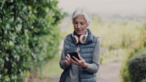 Phone,-fitness-and-senior-woman-at-park-outdoor