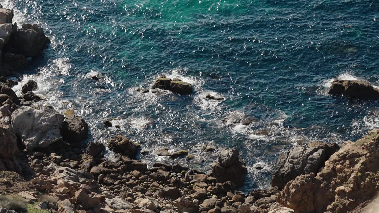 Waves crash against the rocky shoreline with textured cliffs along Tangier’s coast