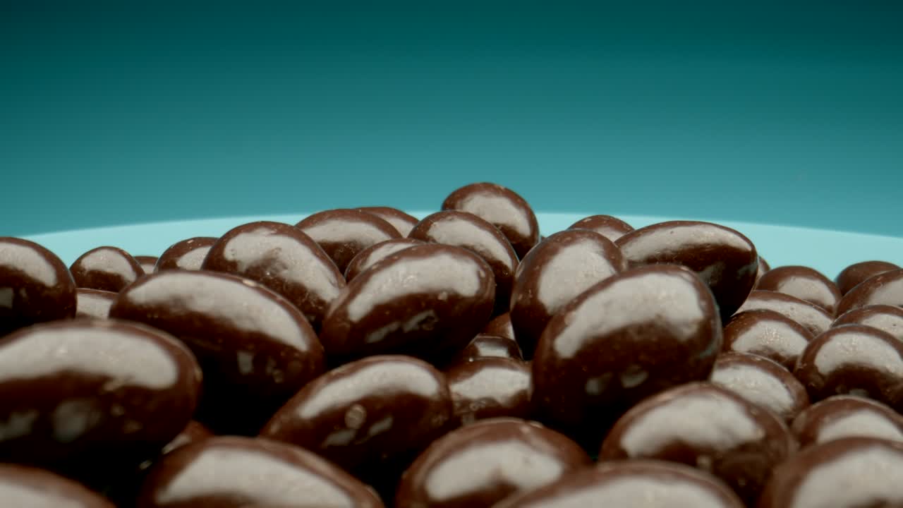 macro: muchos caramelos de chocolate en un plato azul, movimiento de muñeco