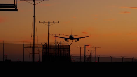 Airplane-on-final-approach-and-landing-against-an-orange-sunset-sky-at-LAX-airport---Los-Angeles