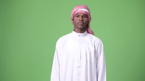 young african man wearing traditional muslim clothes against green background