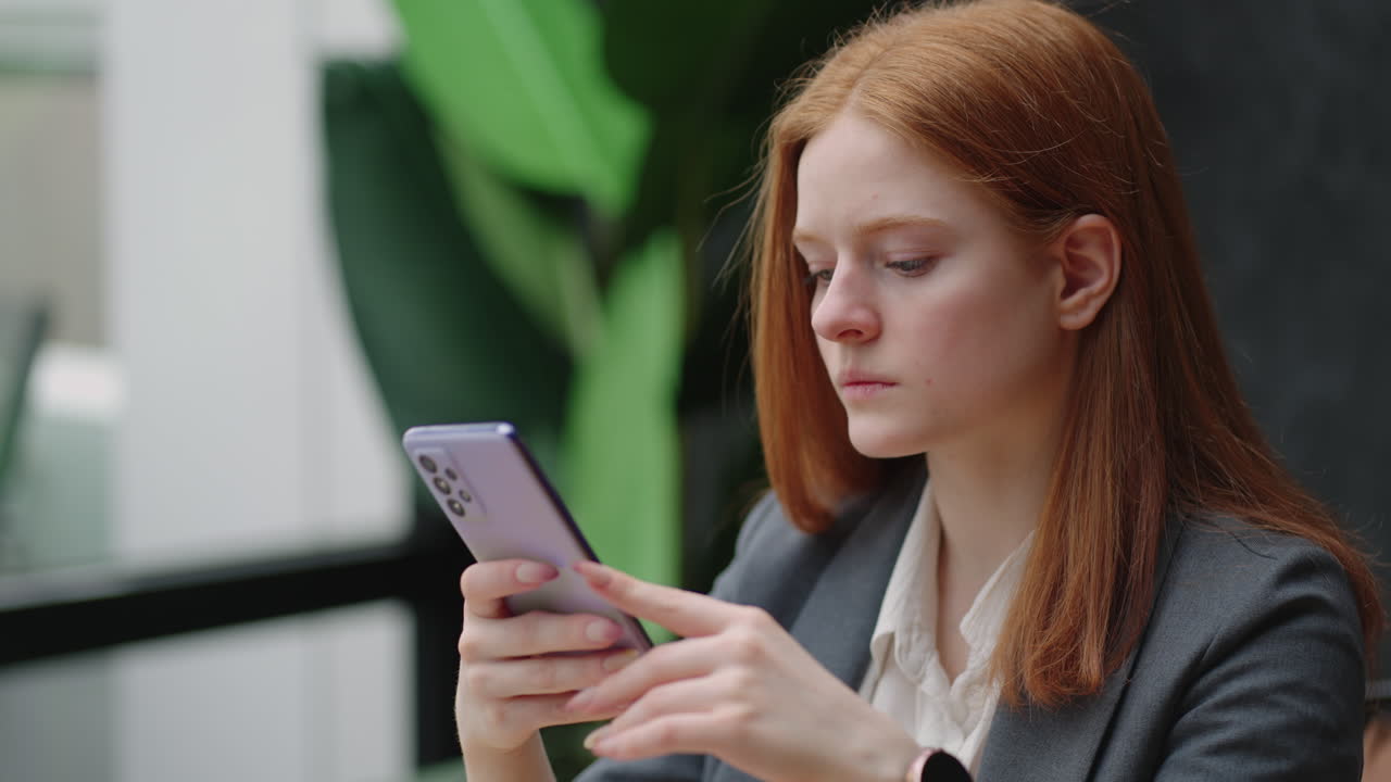 una mujer de negocios seria está leyendo noticias y navegando por internet con su teléfono inteligente en busca de información