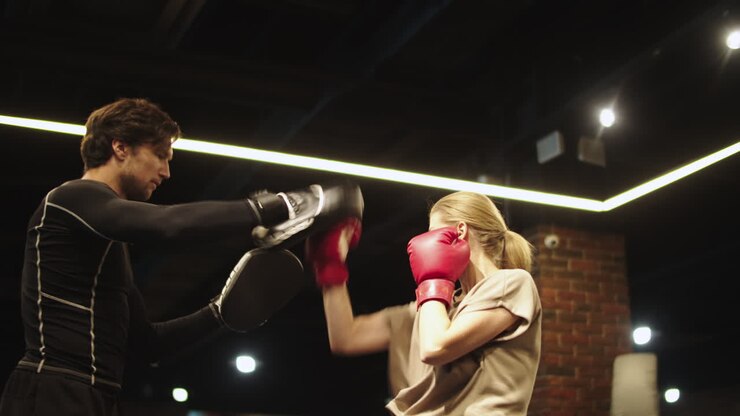 Donna sportiva ansiosa che fa boxe in un centro sportivo. Pugili maschi e femmine che si allenano in palestra.