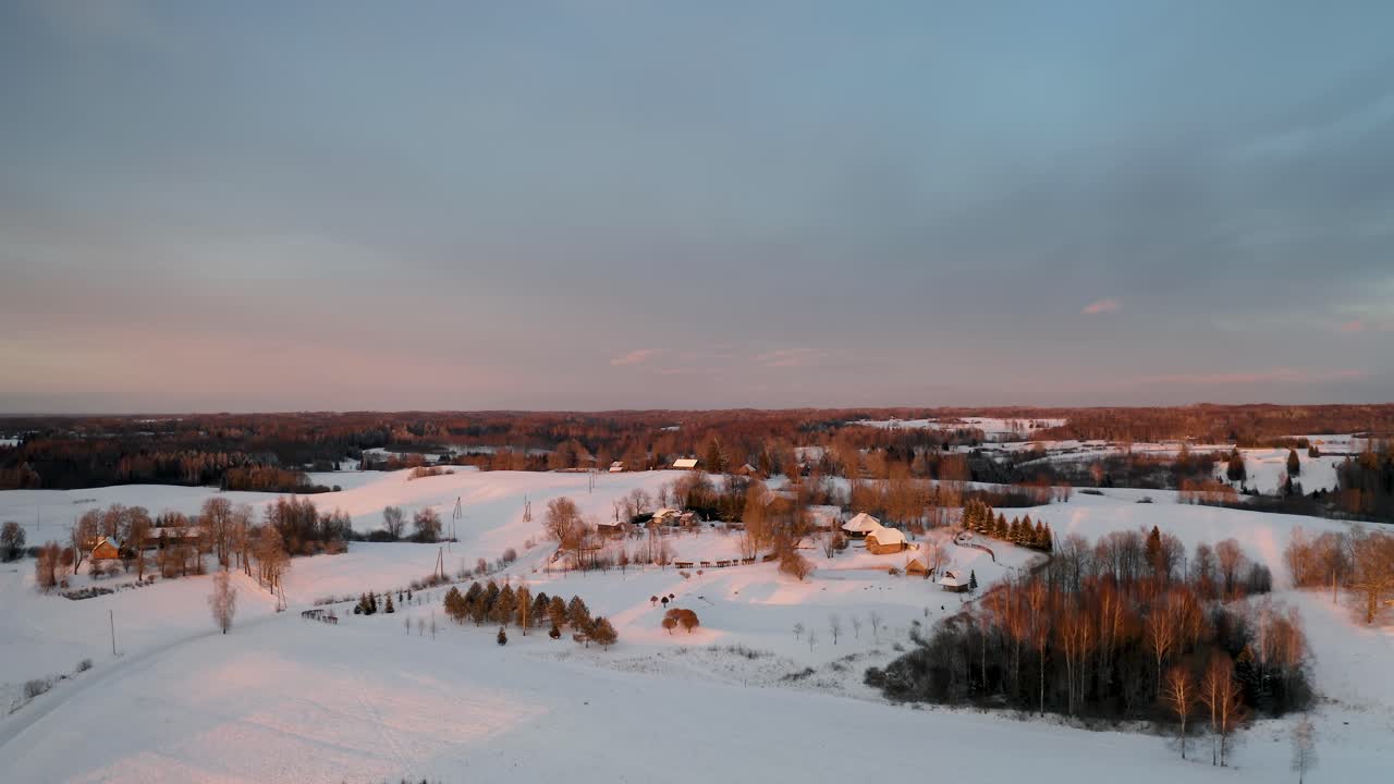 Aerial view of a household community in the countryside during winter with lots of snow. Multiple family houses in suburbs at vibrant sunset.