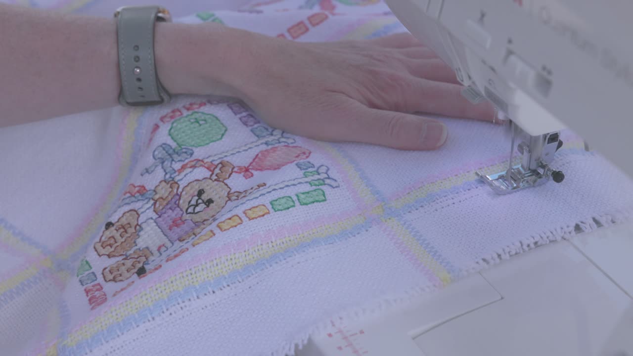 A seamstress using a sewing machine to stitch a border on a baby blanket