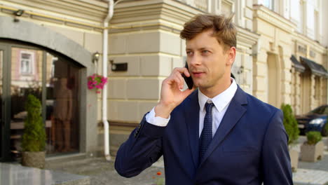 Portrait-man-talking-cellphone-at-street.-Businessman-using-smartphone-outdoors