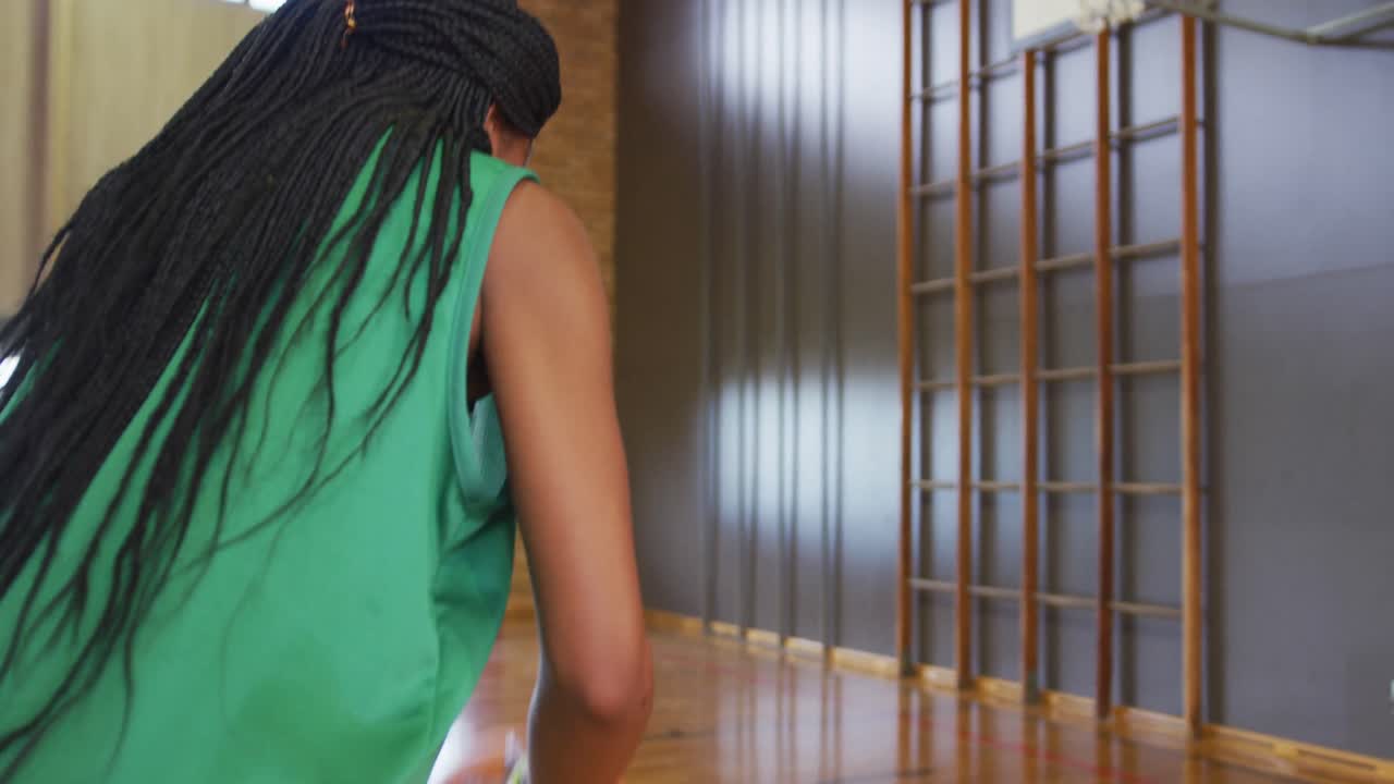 African american female basketball player dribbling and shooting with ball