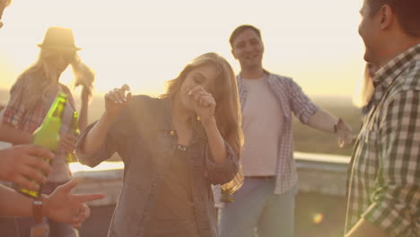 la mujer está bailando y sonriendo en el techo con sus amigas en la fiesta. su cabello rubio está volando en el viento. está bailando con sus brazos y cuerpo.