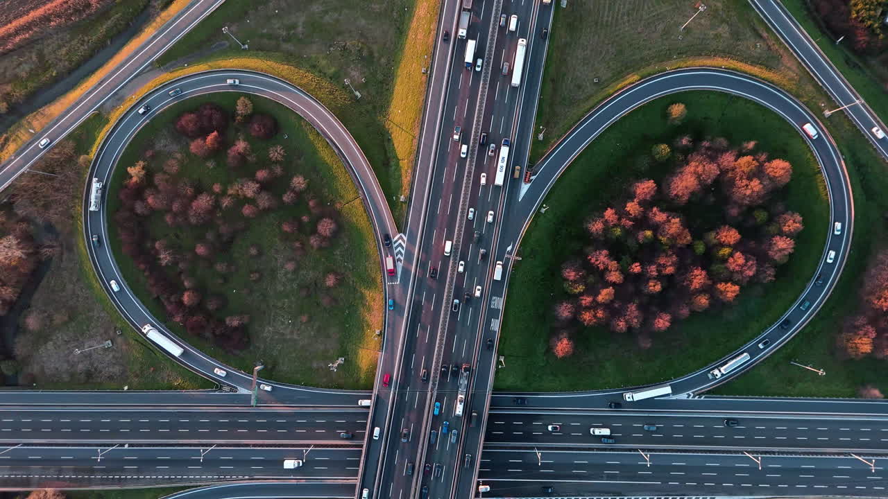 Aerial view of highway interchange with autumnal foliage, traffic moving
