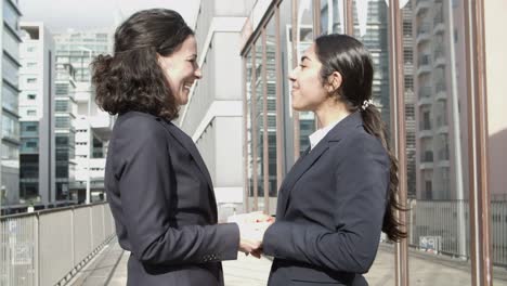 businesswomen greeting each other and talking on street