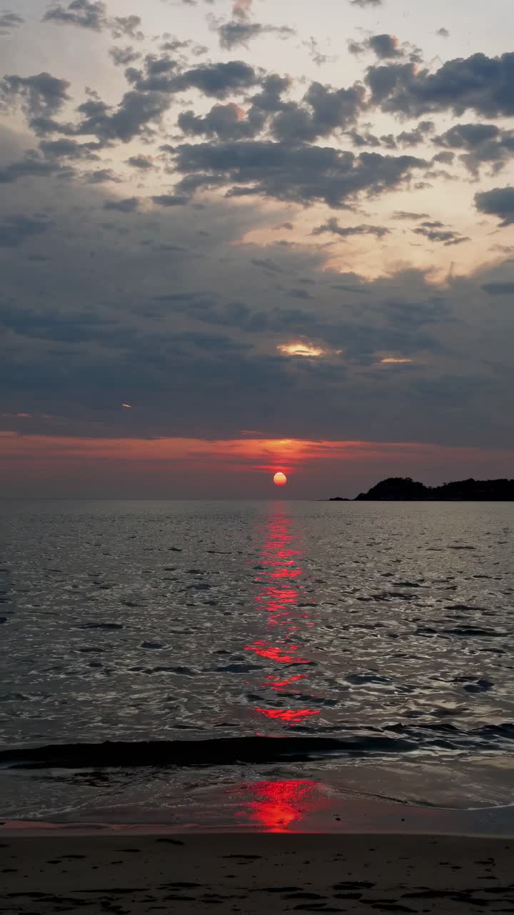 A serene sunset over the ocean, captured at eye level. The video showcases vibrant colors reflecting