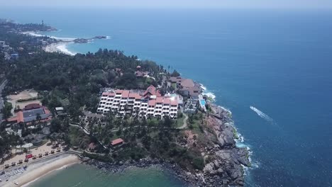 Leela-Kovalam-Hotel-Overlooking-Scenic-Blue-Sea-In-Kerala,-India---drone-pullback