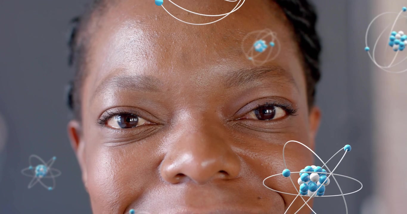 Woman opening eyes and activating orbiting atomic clusters around face for science visualization