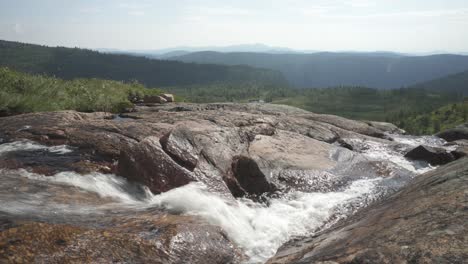 Tranquil-highland-stream-cascading-down-rocky-mountainside,-slider-shot