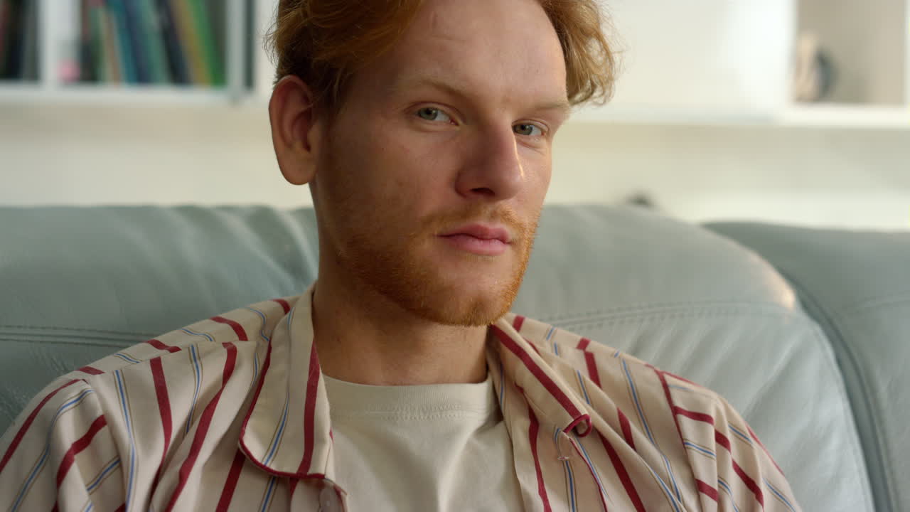 размышляющий менеджер позирует дома вблизи, задумчивый рыжий парень отдыхает после работы.