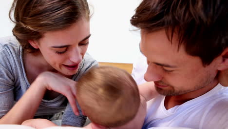padres felices acostados con su lindo bebé en la cama