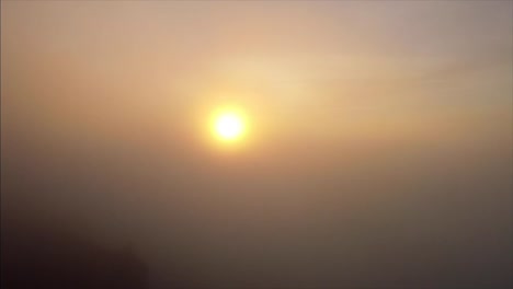 drone rising through fog and clouds to reveal sunset over the canyon