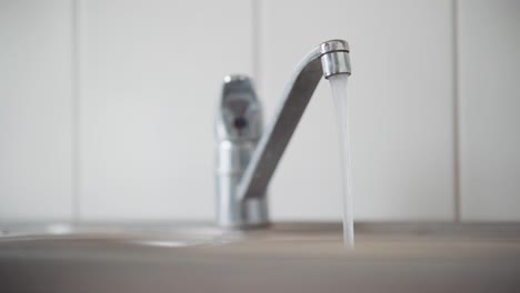 hombre poniendo un vaso debajo de un grifo en funcionamiento y llenándolo con agua