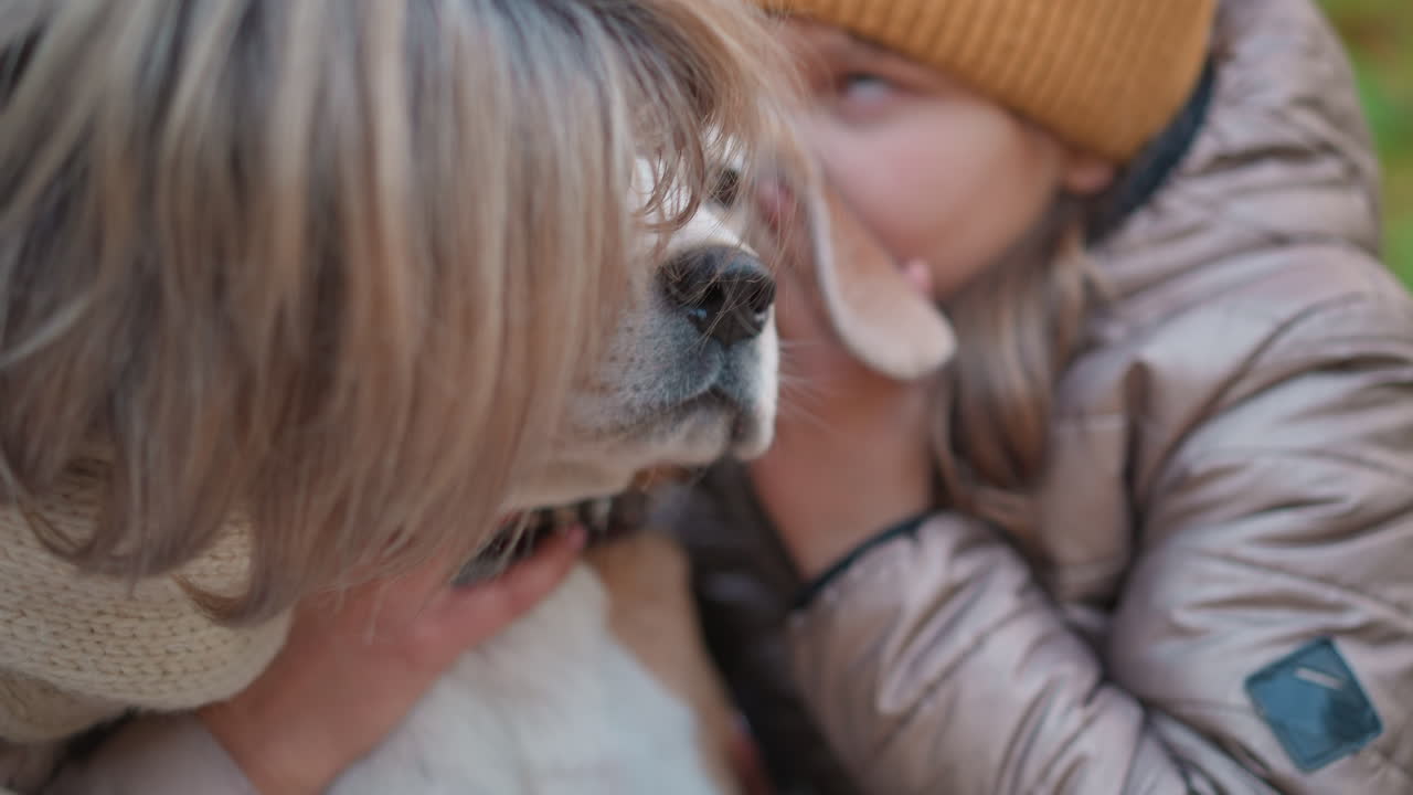 woman and child kiss dog gently while holding it close in warm autumn outdoor scene reveals emotional connection, soft natural lighting, cozy jackets and scarves enhance intimate moment