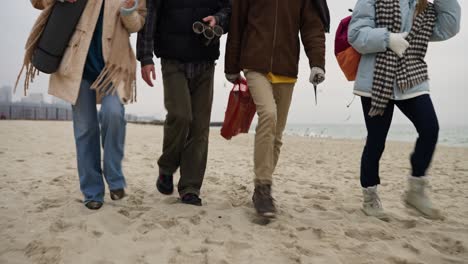 four people walking on a beach in winter
