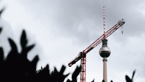 Encantador-Timelapse-Donde-Veloces-Nubes-Cruzan-El-Cielo-De-Berlín,-Con-La-Fernsehturm-Y-Una-Grúa-Estacionaria-Como-Espectadores-Estoicos-De-La-Actuación-De-La-Naturaleza.