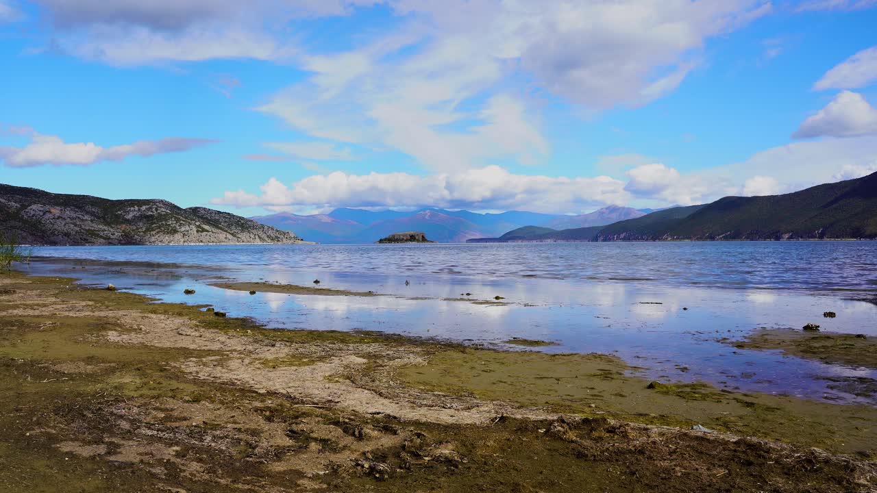 tranquilo lago de prespa en otoño con costa seca y aguas tranquilas que reflejan nubes blancas en el cielo azul