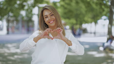 Mujer-Joven-Feliz-Mostrando-El-Corazón-De-La-Mano