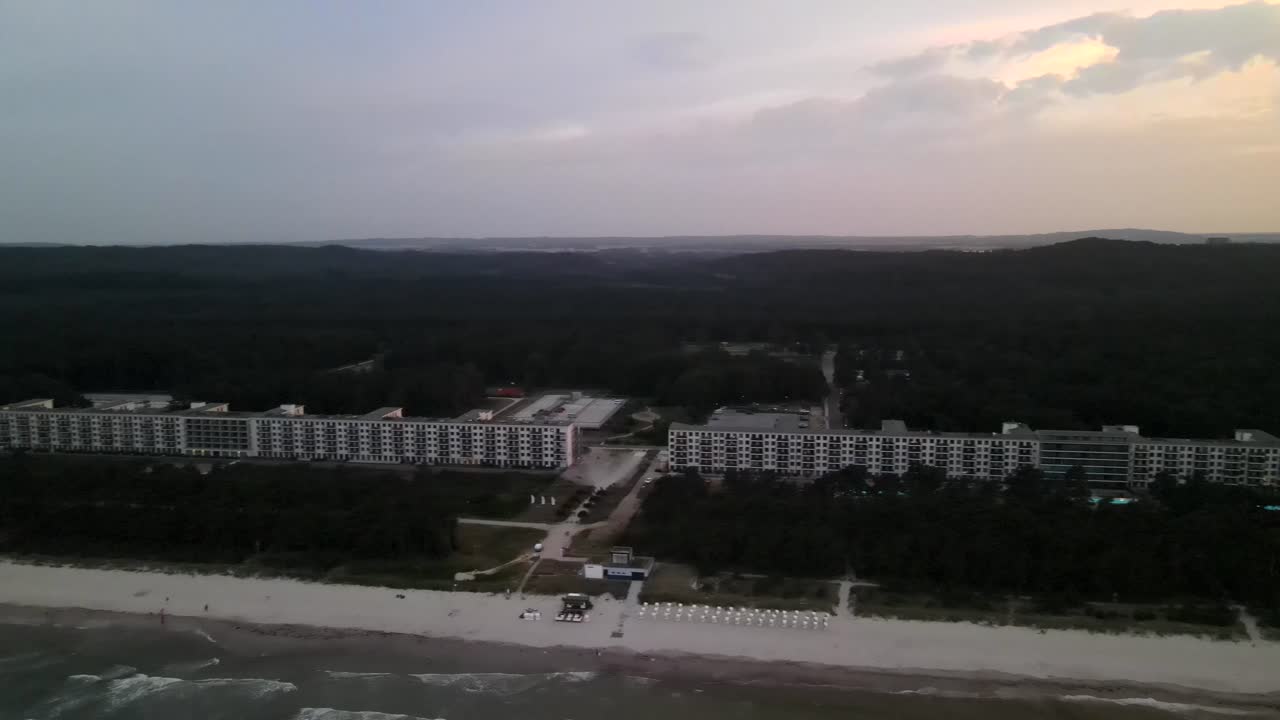 Golden sunset at Prora beach on Rügen, with waves rolling in and the historic seaside complex lining the tranquil coast.