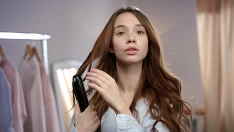 una mujer hermosa peinando el cabello con hierro.