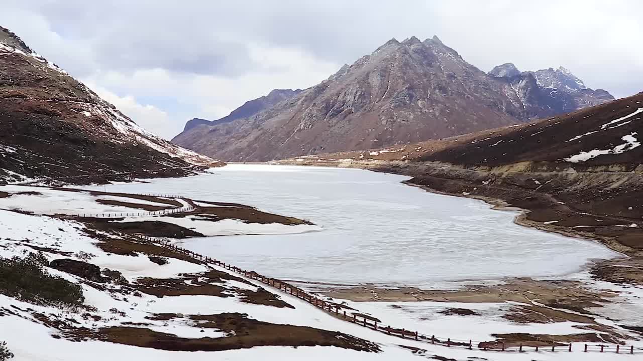 lago sela congelado con montañas cubiertas de nieve y cielo azul brillante por la mañana desde un video de ángulo plano tomado en sela tawang arunachal pradesh india
