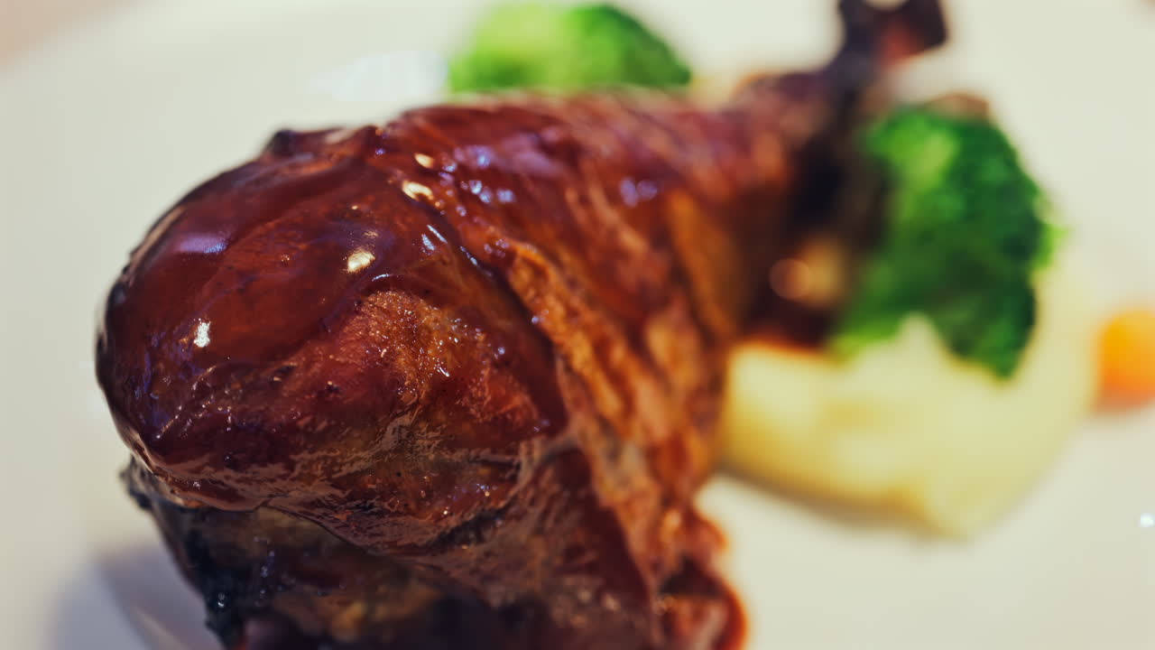 Close up of chocolate pouring on a slice of cheesecake on a white plate
