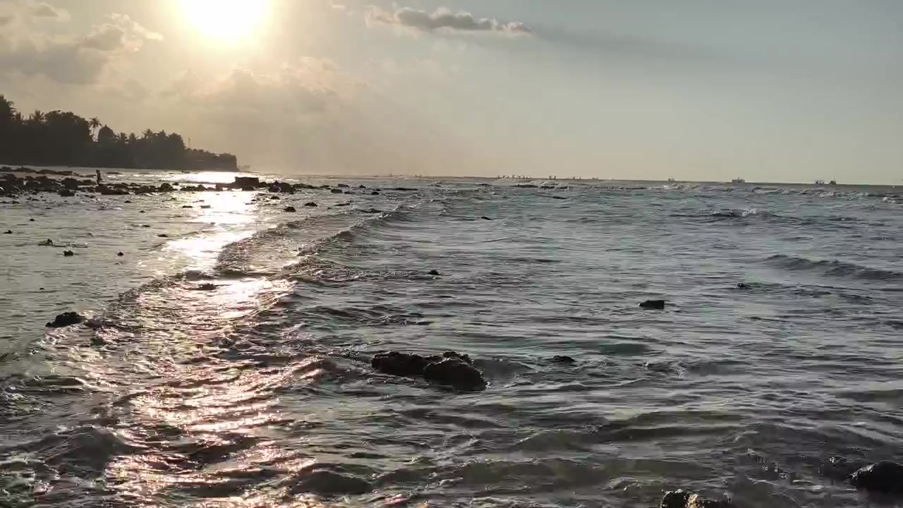 Onde leggere che si infrangono su una spiaggia rocciosa al tramonto