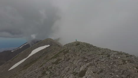 aerial view of a hike woman and man that walk on a mountain peak during a foggy day