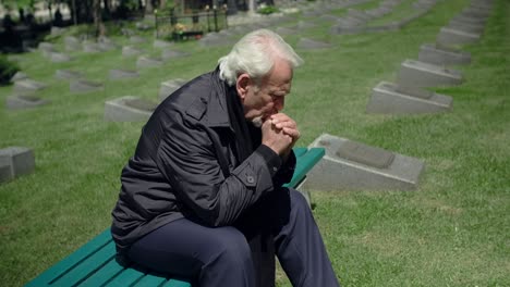 elderly man mourns at cemetery
