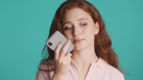 redheaded girl in front of camera on turquoise background.