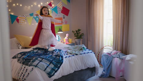 niña feliz saltando en la cama vistiendo disfraz jugando a un juego disfrutando de la imaginación juguetona en un dormitorio colorido en casa
