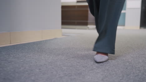 close-up shot of businesswoman walking confidently in office with elegant gray shoes, stylish wide pants, and modern office background